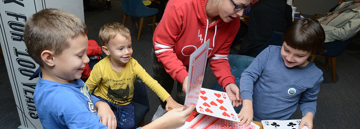 Three young boys enjoy playing games with giant playing cards at Fun Palace